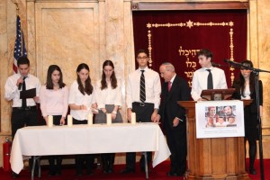 Rabbi Haskel Lookstein and students of the Ramaz Upper School lighting memorial candles for Ehud (36), Ruth (35), Yoav (11), Elad (4), and Hadas (3 months) Fogel.