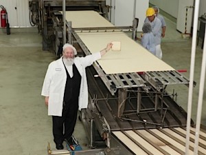 Rabbi Yaakov Y. Horowitz, Manischewitz's chief rabbi, holding up a piece of regular matzah next to the 25-foot-long world record-holding matzah, at the Manischewitz factory in Newark, NJ, in 2011. 