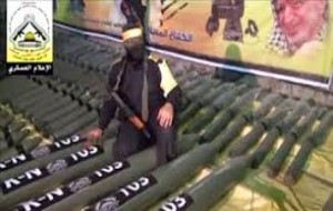 aqsa rockets An Al Aqsa Martyrs' Brigade soldier kneeling atop a cache of rockets, in front of a portrait of former PLO chairman and architect of Palestinian nationalism, Yasser Arafat. Photo: Screenshot / Nedal.