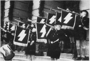 Hitler Youth Hour of Commemoration in front of the Town Hall in Tomaszow, Poland during German-Nazi occupation, May 11, 1941. Photo: US National Archives and Records Administration via Wikimedia Commons.