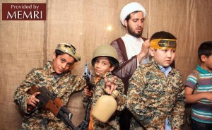 Cleric puts combat headbands on uniformed children holding weapons during City of Resistance Games. Photo: MEMRI.