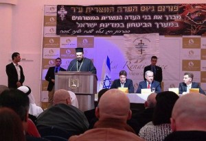 Father Gabriel Naddaf addresses Christian IDF soldiers in December 2014, with Israeli Prime Minister Benjamin Netanyahu (sitting at table in center) in attendance. Photo: Maor X via Wikimedia Commons.