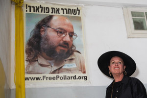 Esther Pollard, wife of convicted Israeli spy Jonathan Pollard, walks past a poster of her husband prior to speaking to press outside her home in Jerusalem on July 29, 2015. Israeli agent Jonathan Pollard will be released from prison after serving 30 years of a life sentence on November 20, the US Parole Commission announced. Photo: Flash90
