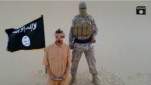 An ISIS video shows a man wearing a yellow jumpsuit kneeling in the desert before a knife-wielding masked man in military fatigues. Photo: Screenshot.