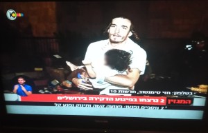 A man at the scene of Saturday evening's terrorist attack in Jerusalem carrying the two-year-old baby with stab wounds in his leg to nearby paramedics. Photo: Channel 10/screenshot.