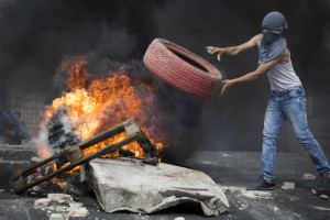 On Oct. 7, 2015, a Palestinian rioter throws a tire into a fire, blocking a road during clashes with Israeli police in eastern Jerusalem. Photo: Hadas Parush/Flash90.