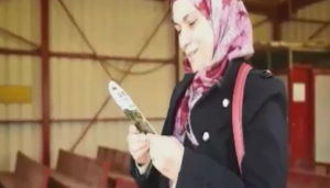 A Palestinian woman reacts to being handed a packet of cucumber seeds at a checkpoint. Photo: Screenshot.
