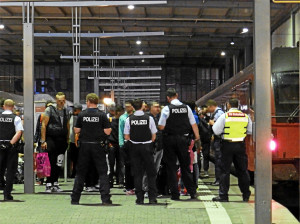 German police guard a train station, where asylum-seekers gather. Photo: Wikipedia.