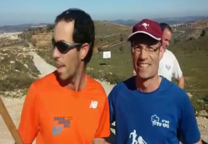 Tomer Ditur (L) was stabbed during a jog on Tuesday, and running again Friday. He is joined by Gush Etzion Regional Council Chair Davidi Perl (R). Photo: Screenshot