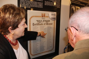 Standing in front of a poster at the Tel Aviv's Beit Hatfutsot museum with a list of individuals who had saved Jews in Drohobych-Boryslav during the Holocaust, Irena Wysoki points to the names “Jan Sawiński” and “Zofia Sawińska,” Polish farmers who hid Wysoki and her brother. Photo: Eitan Arom.