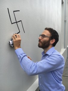 Rabbi Yossi Friedman seen cleaning a swastika graffitied on the Maroubra Synagogue in Sydney. Photo: Courtesy. 